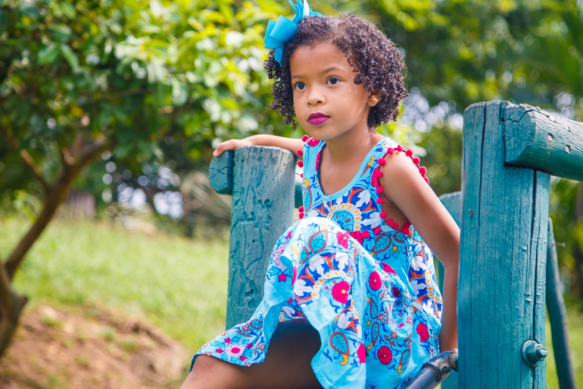 Criança sentada, olhando para frente, durante ensaio fotográfico em Belo Horizonte.