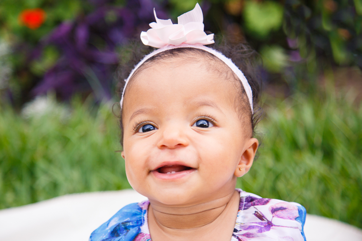 Criança olhando para a mãe, que não aparece na foto, e sorrindo.