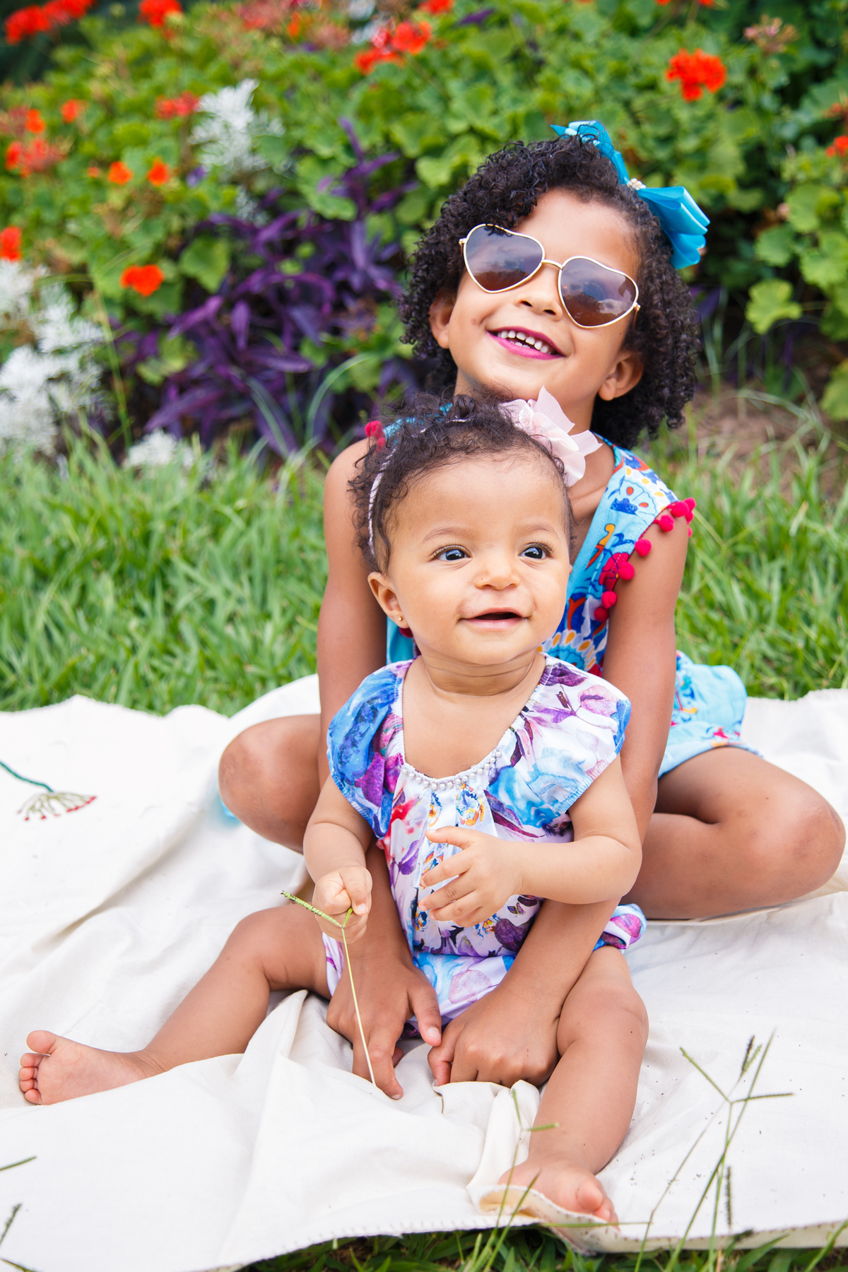 Duas irmãs se abraçando sentadas no chão, durante ensaio fotográfico.
