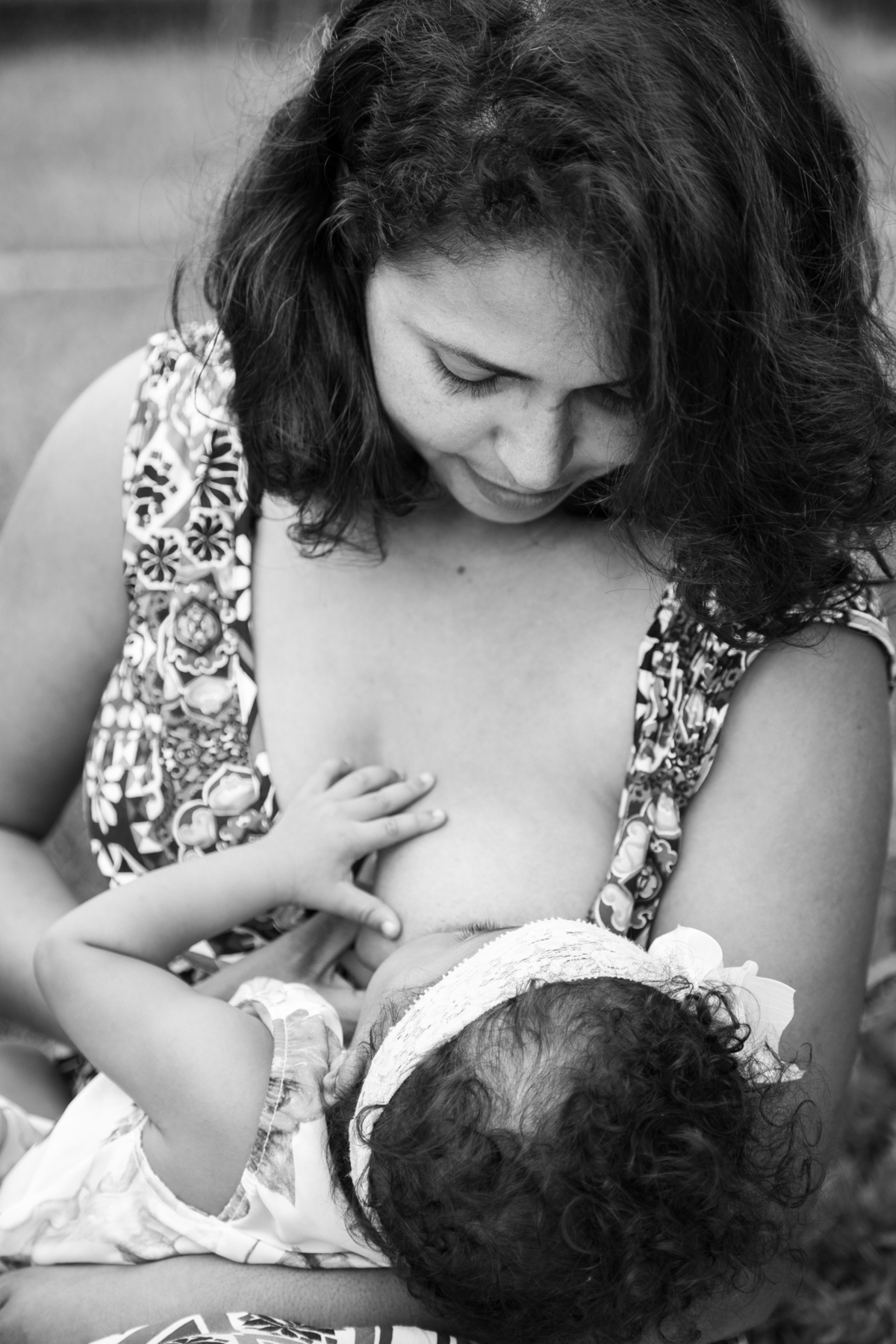 Foto em preto e branca da mãe amamentando sua bebê, as duas se olhando.