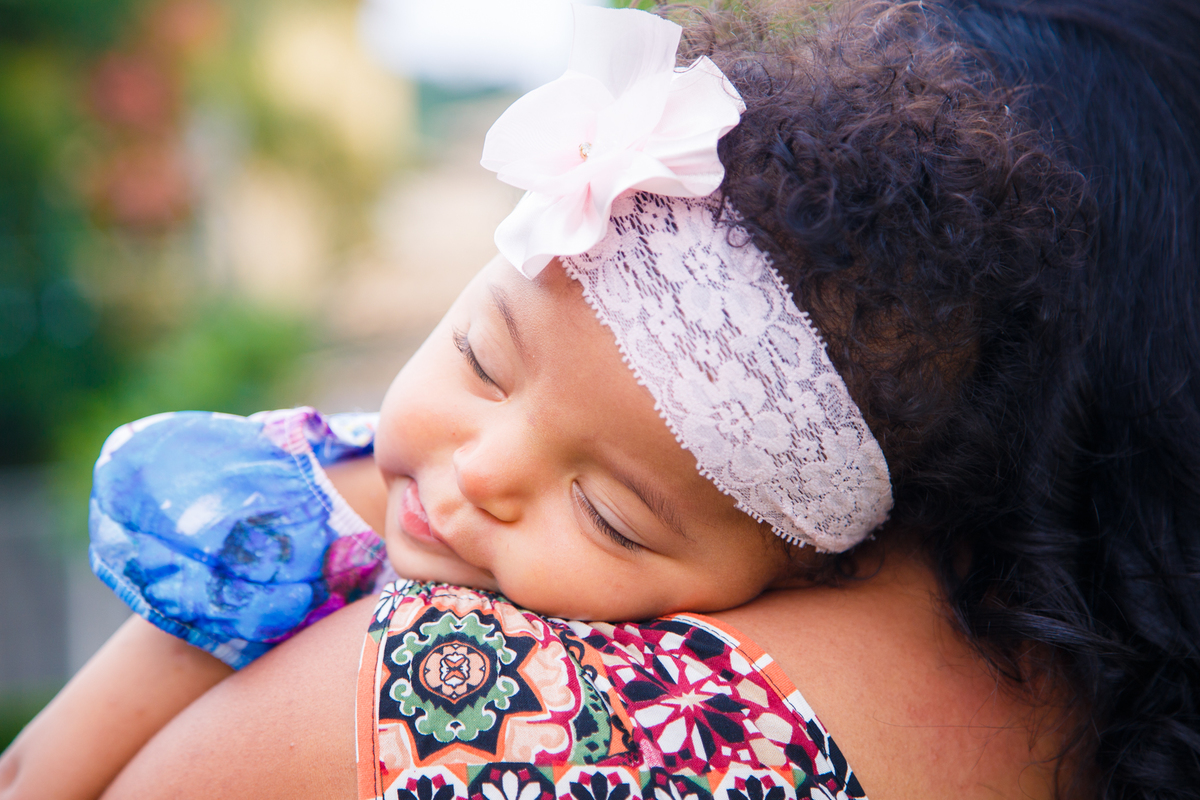 Bebê dormindo no ombro de sua mãe após mamar.