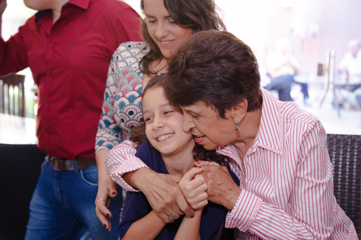 Criança ganhando um abraço de uma senhora em uma festa de aniversário infantil.