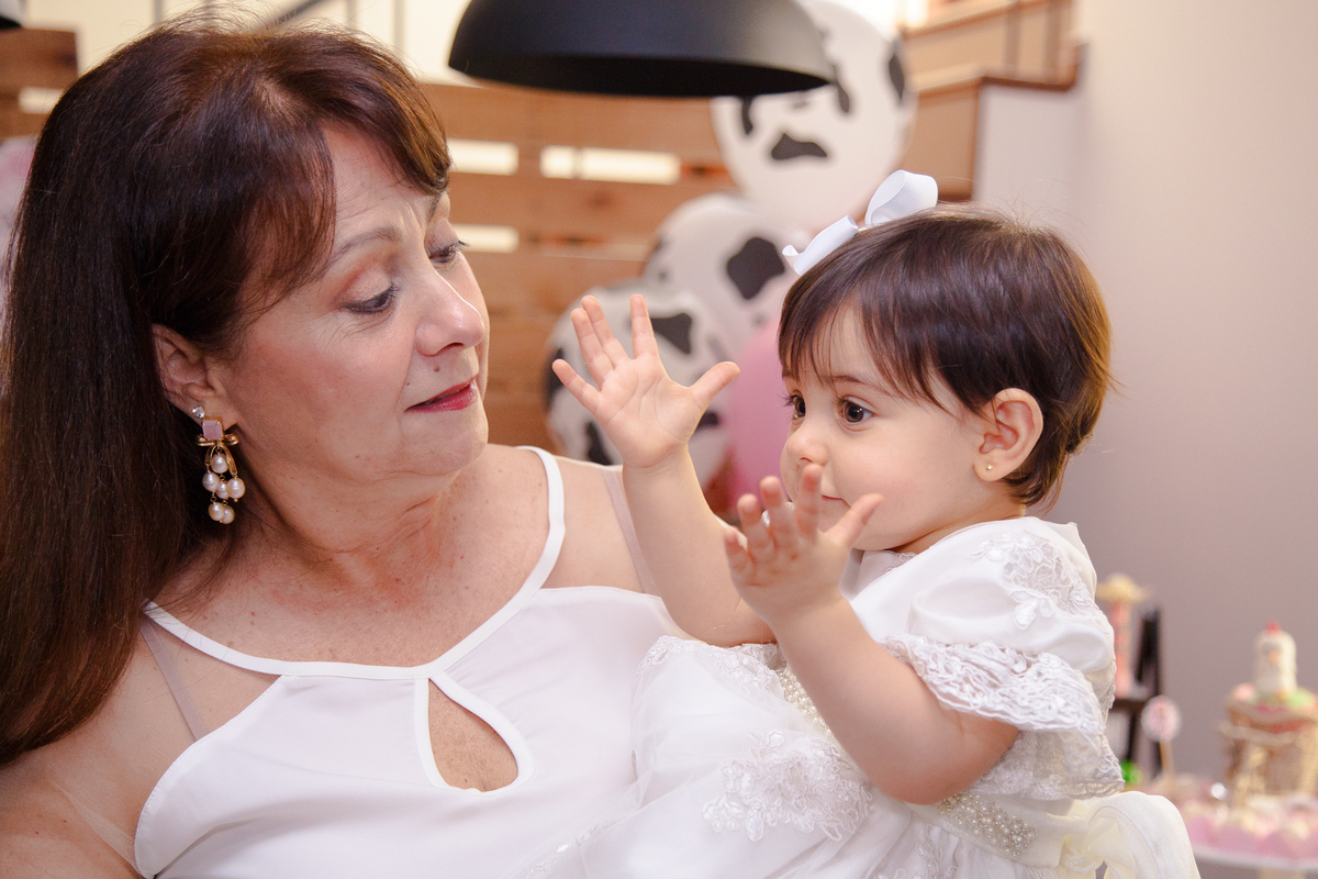Bebê de 1 ano batendo palminhas no colo de sua avó, em seu aniversário de 1 ano.