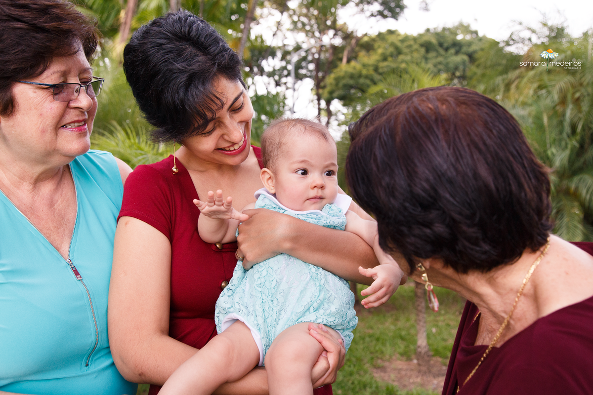 Bebê no colo da mãe observando e sendo observada pela bisa, pela avó e pela mãe.