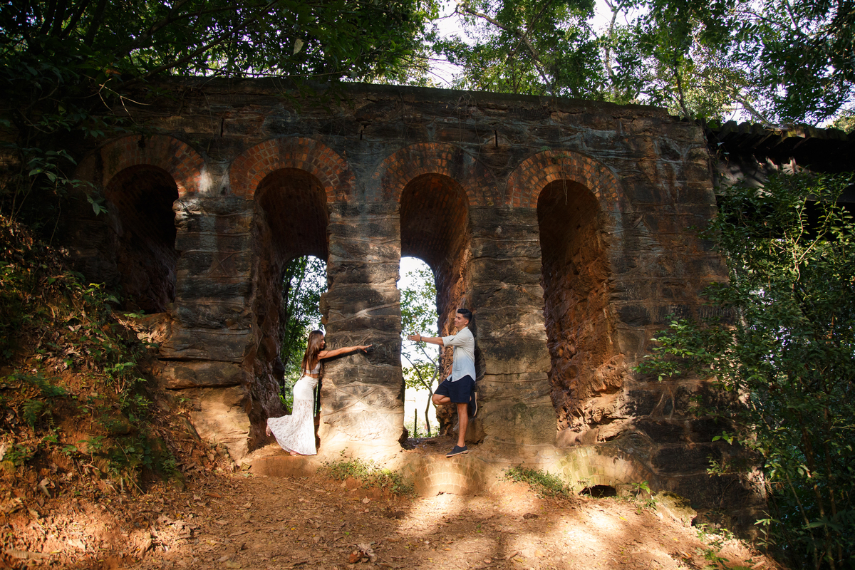 Foto panorâmica de um casal brincando nos vãos de uma ruína de trilho de trem em uma cidade próxima a Belo Horizonte.