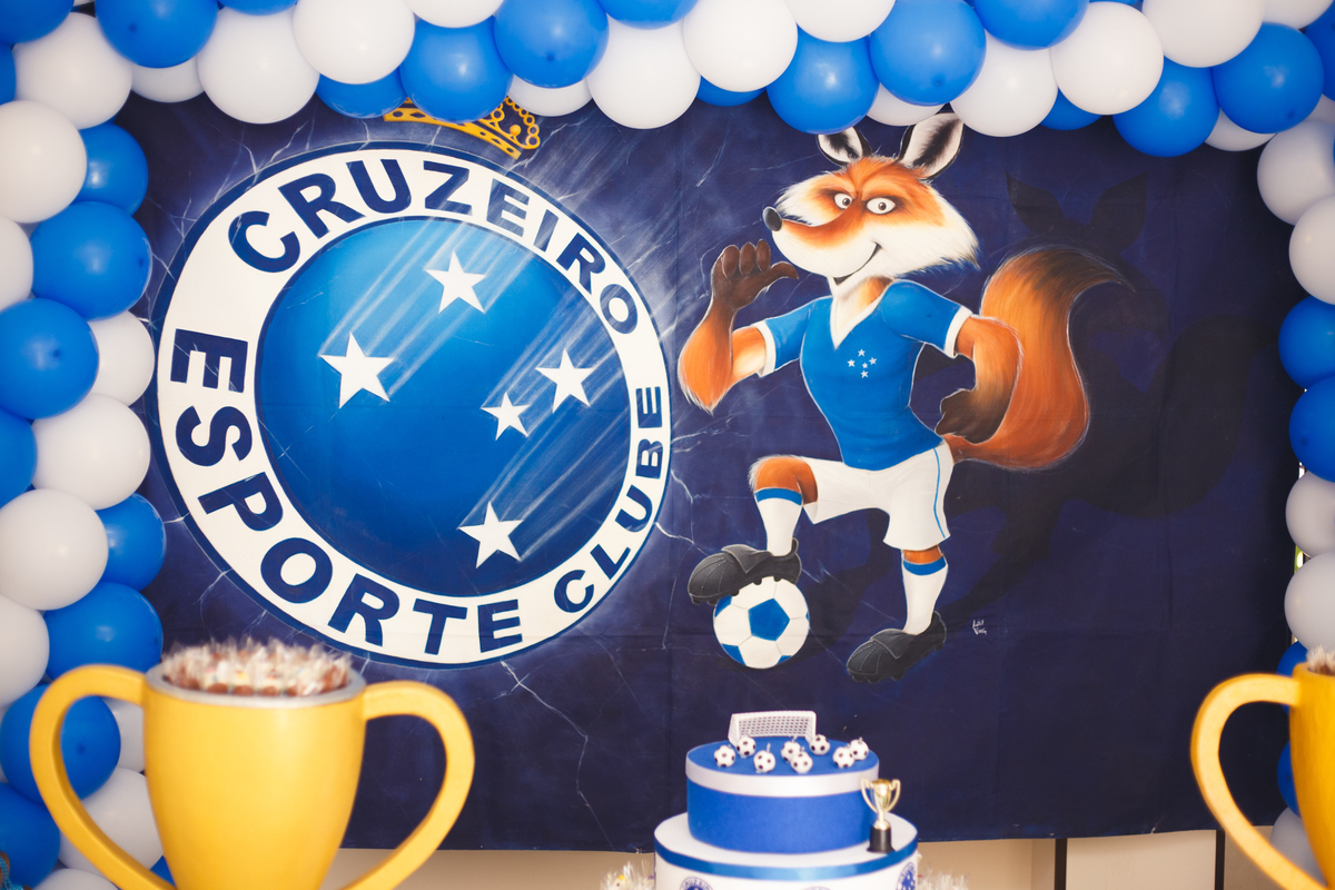 Detalhe do painel ao funda da mesa do bolo no tema futebol, com o escudo e mascote do cruzeiro.