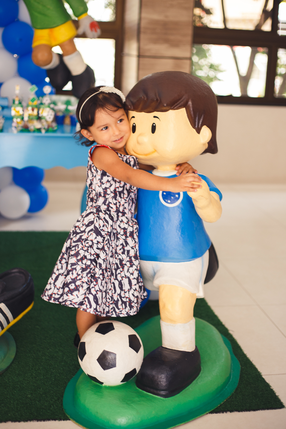Criança abraçando o boneco de decoração, fingindo que está dançando com ele e com um leve sorriso.
