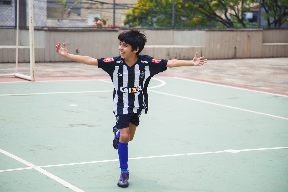 Criança com camisa do galo comemorando um gol no aniversário infantil.