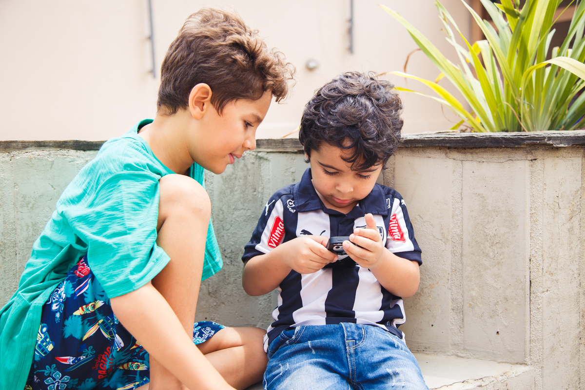 Duas crianças brincando com um celular em uma festa de aniversário infantil.