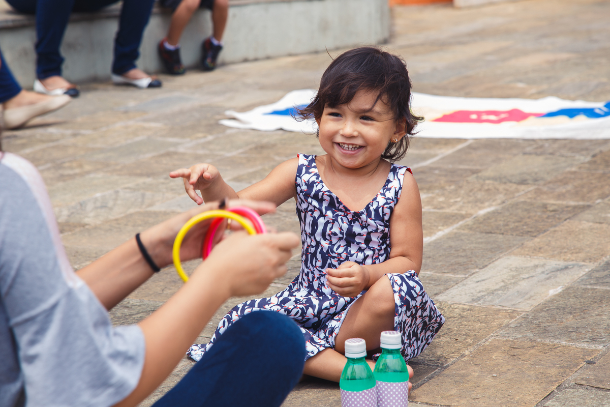 Criança sorrindo e brincando com a prima mais velha, com argolas.