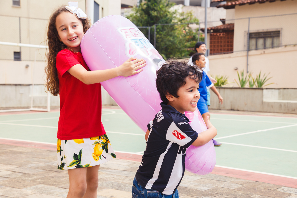 Duas crianças carregando um joão bobo e sorrindo.