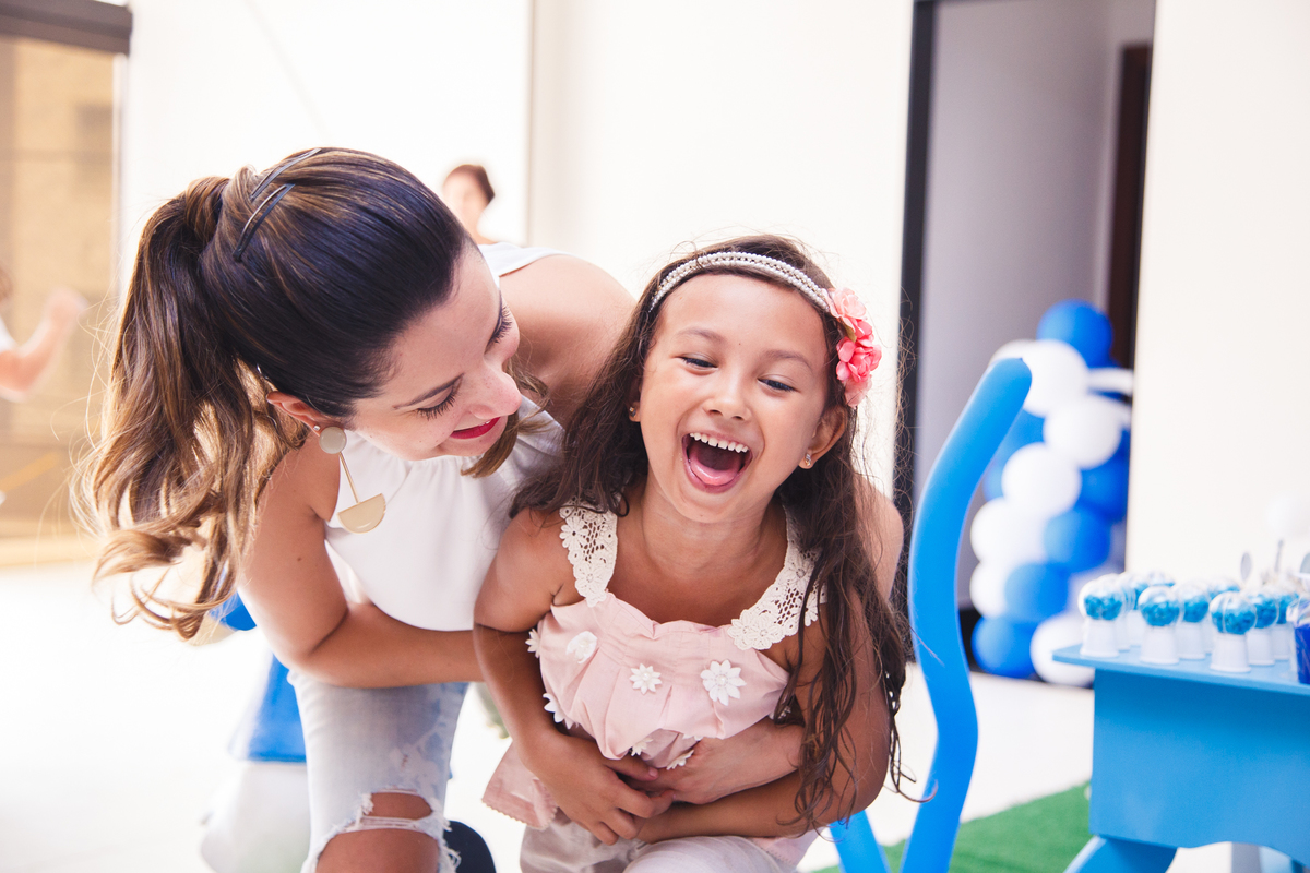 Tia fazendo cócegas na sobrinha que dá uma enorme gargalhada.