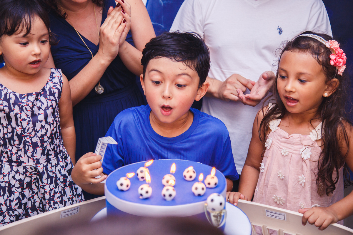 Aniversariante atrás da mesa do bolo soprando as velas em seu aniversário.