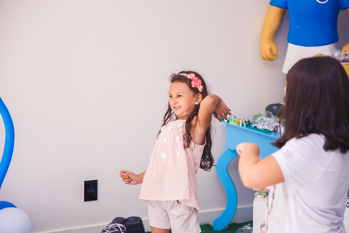 Criança com uma bolinha na mão se preparando para arremessar em alguém, fazendo uma careta com a concentração para conseguir jogar longe.