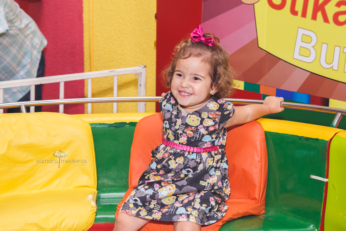 Criança no brinquedo gira gira, segurando na barra e com um sorriso.