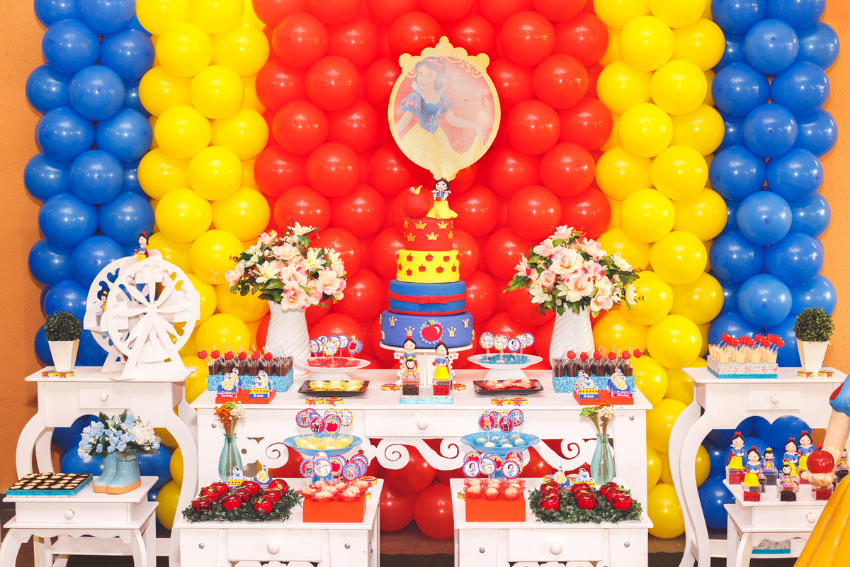 Mesa do bolo e decoração no tema Branca de Neve de um aniversário infantil de 9 e 3 anos.