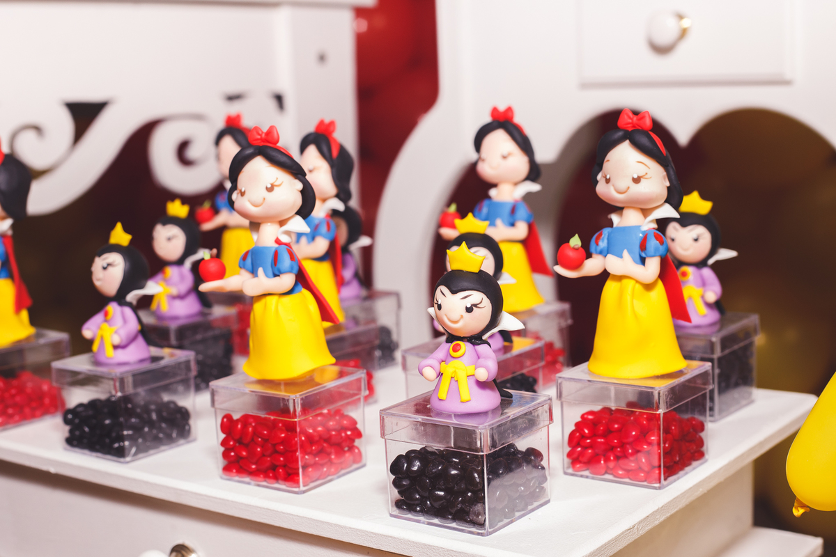 Detalhe da decoração de uma festa de aniversário infantil, com caixinhas de plástico com balas coloridas e bonecas de biscuit.