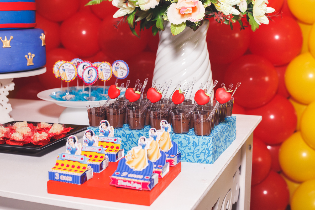 Detalhe da mesa do bolo de um aniversário infantil, com doces e alguns personalizados.