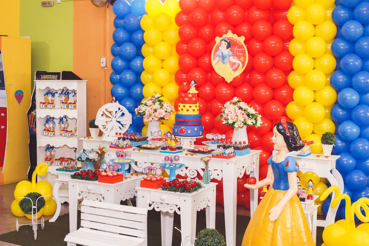 Foto mais ampla da mesa do bolo e decoração da festa infantil no tema Branca de Neve.