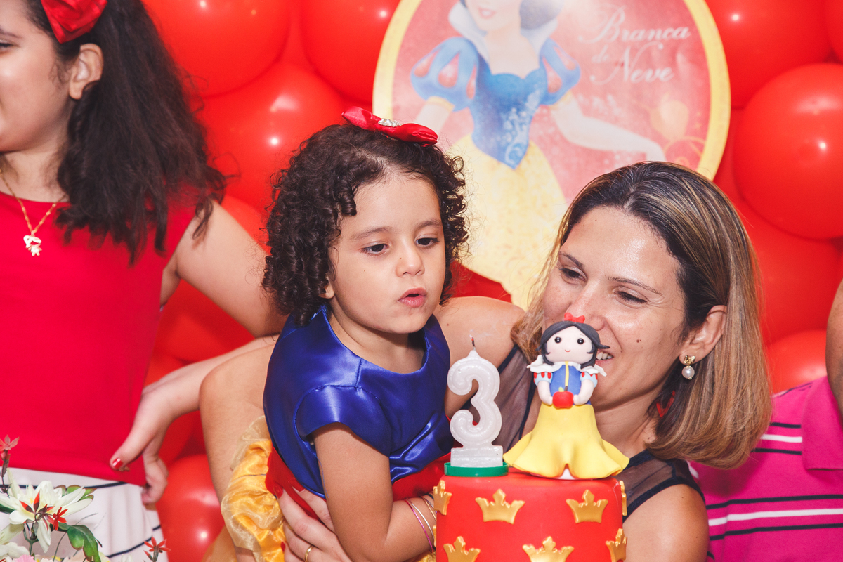 Criança de 3 anos assoprando a velinha em seu aniversário.