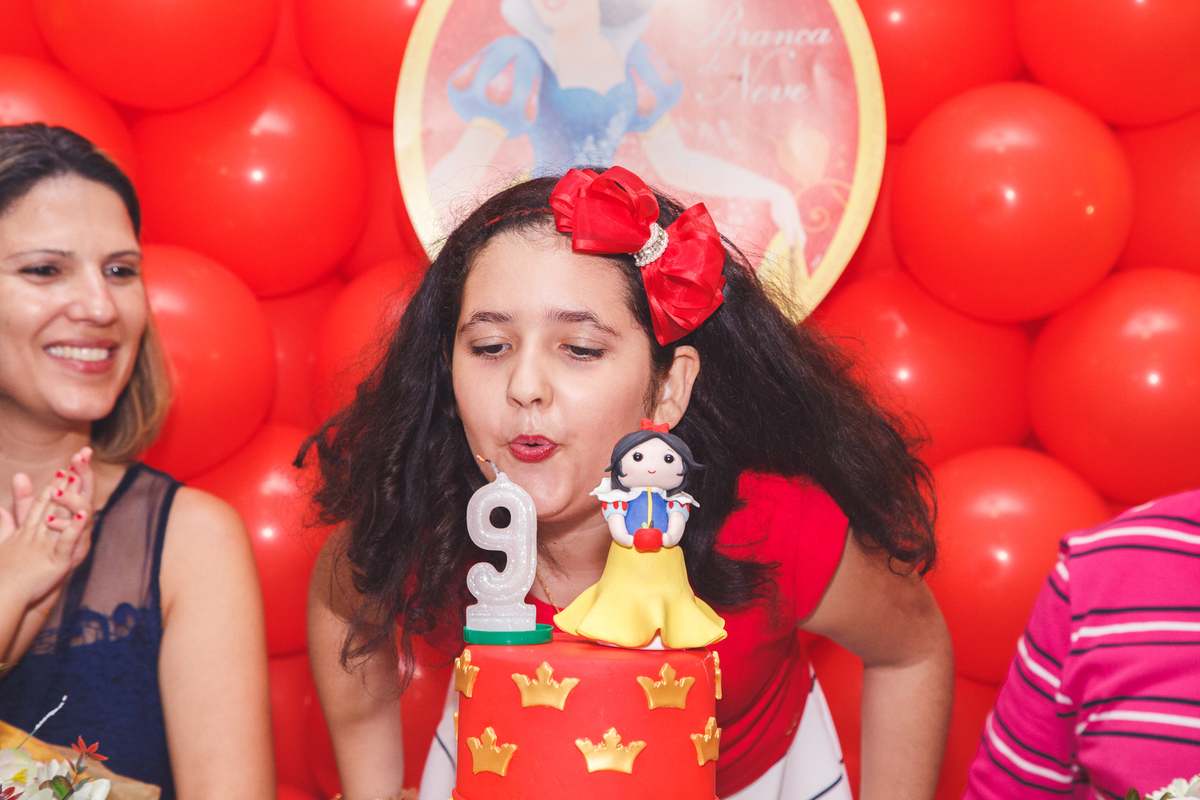 Criança de 9 anos soprando a velinha após o parabéns em seu aniversário.
