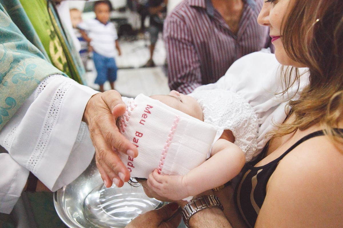Padre secando a cabeça da bebê após o batismo.