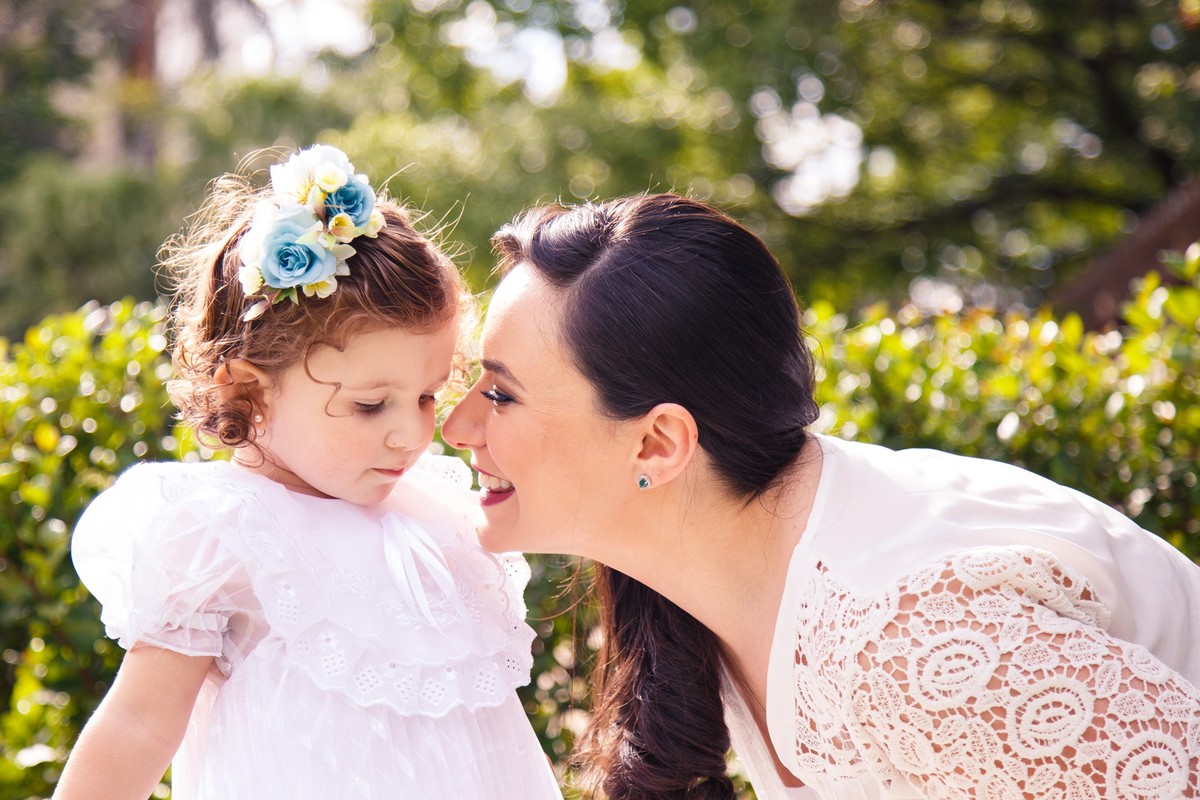 Mãe e criança interagindo, durante um ensaio família, em uma praça.