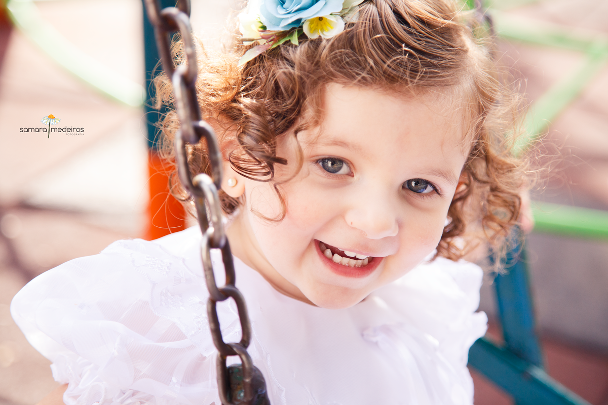 Close em uma criança brincando no balanço, sorrindo e se divertindo no ensaio de família.
