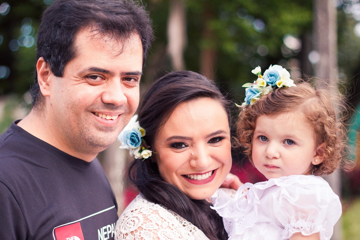 Retrato da família, casal com a filha de 2 anos, todos olhando para a câmera.