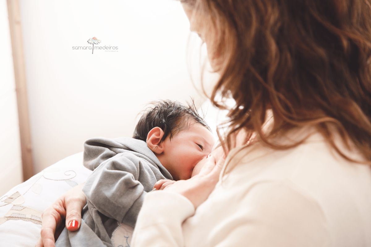 Recém nascido mamando no peito de sua mãe durante ensaio newborn lifestyle.