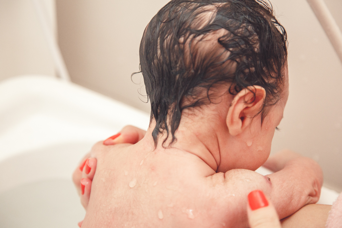 Bebê recém nascido tomando banho em sua banheira, durante ensaio newborn lifestyle.