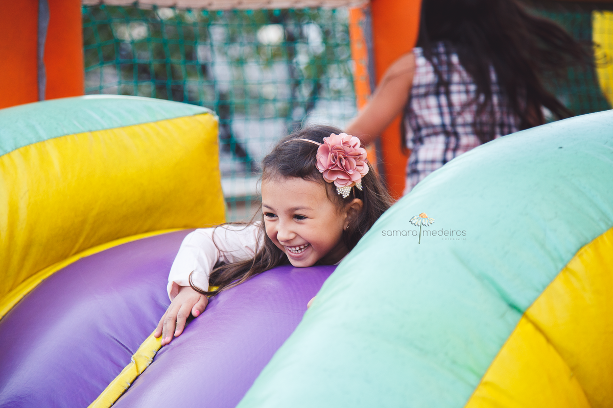 Foto espontânea de uma menina de 6 anos brincando no brinquedo inflável, gargalhando, em seu aniversário de 6 anos,