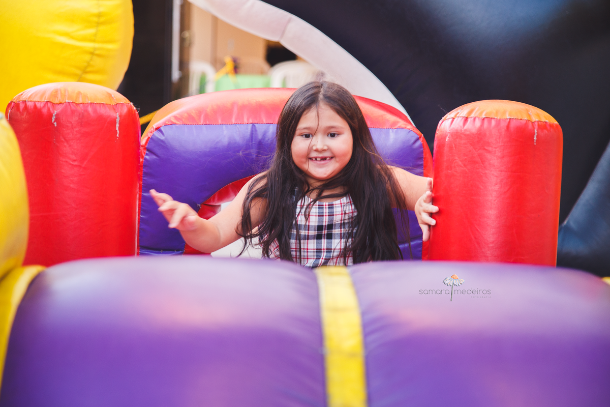 Criança sorrindo enquanto brinca em um brinquedo inflável, em festa de aniversário infantil.