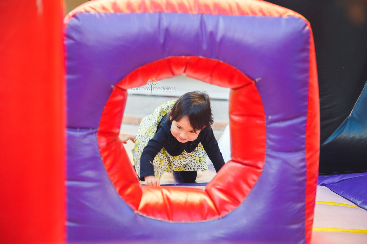 Foto espontânea de uma criança de 3 anos brincando em um brinquedo inflável em sua festa de aniversário de 3 anos.