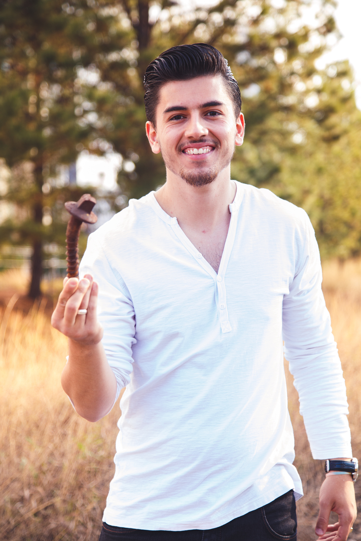 Rapaz com um enorme parafuso na mão, sorrindo para a foto.
