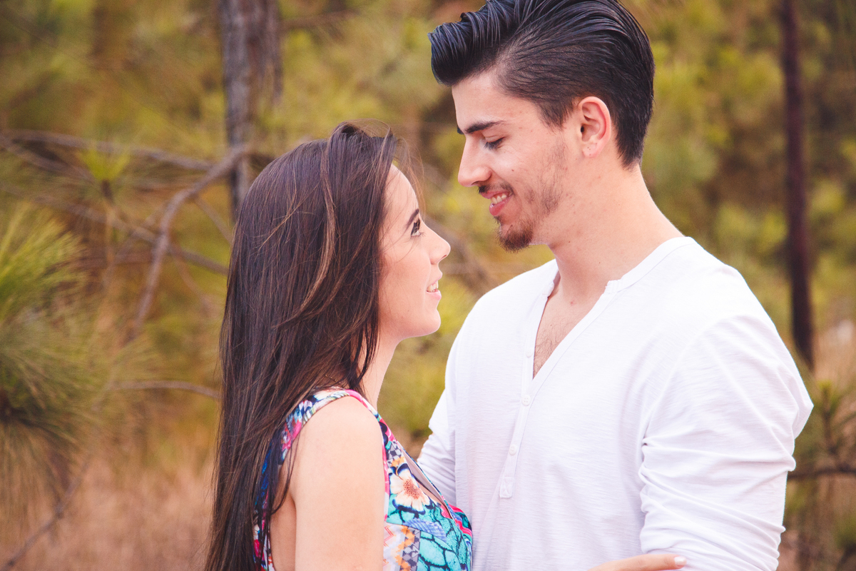 Casal se olhando nos olhos, abraçados, sorrindo, durante sessão de fotos.