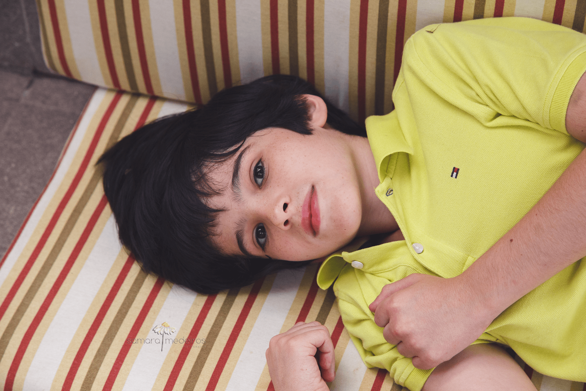 Criança deitada em um sofá, olhando para a foto.