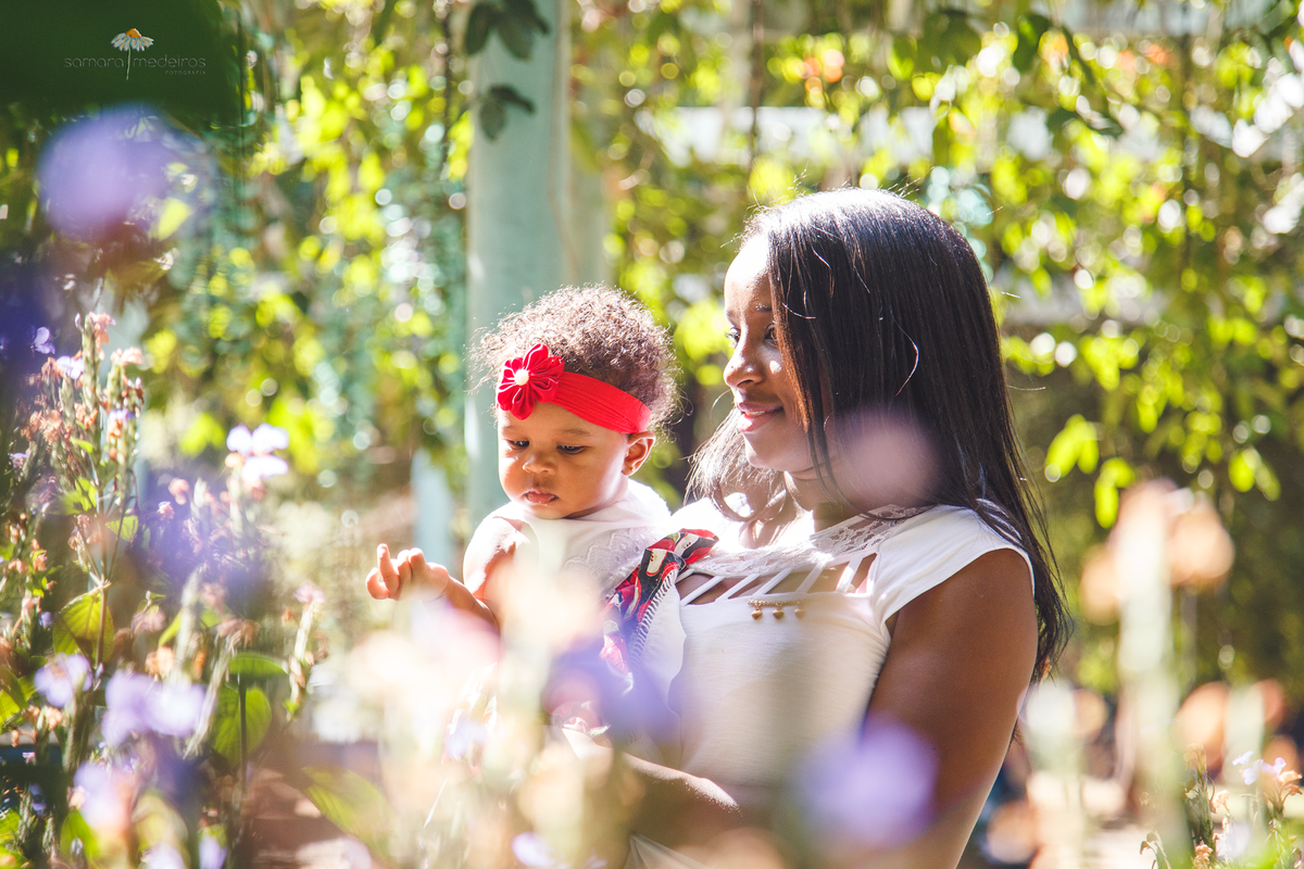 Mãe e filha de pé ao fundo olhando as flores no parque municipal de Belo Horizonte.