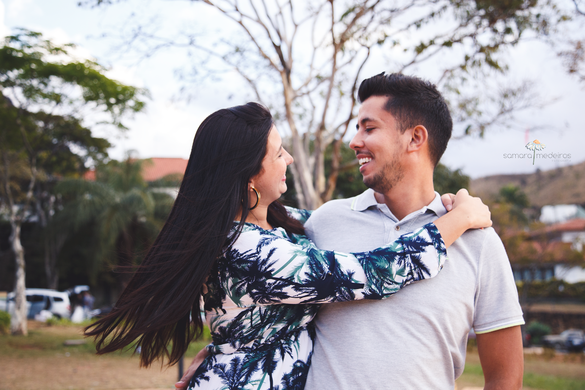 Casal abraçado e sorrindo olhando um para o outro enquanto se divertem durante sessão de fotos de casal.