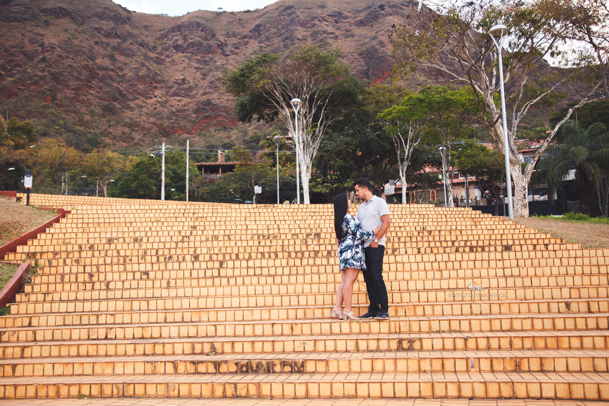 Casal de frente um para o outro na escadaria amarela característica da Praça do Papa em Belo Horizonte.