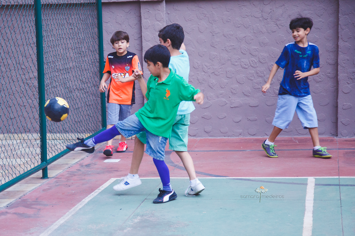 Crianças jogando futebol durante uma festa de aniversário na quadra de um prédio em Belo Horizonte.
