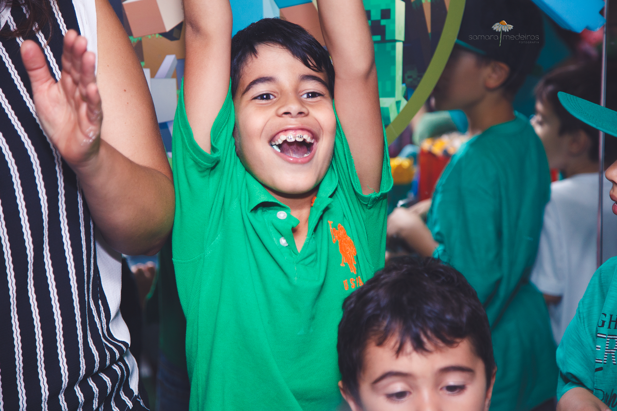 Criança comemorando com os braços para cima após cantar parabéns.