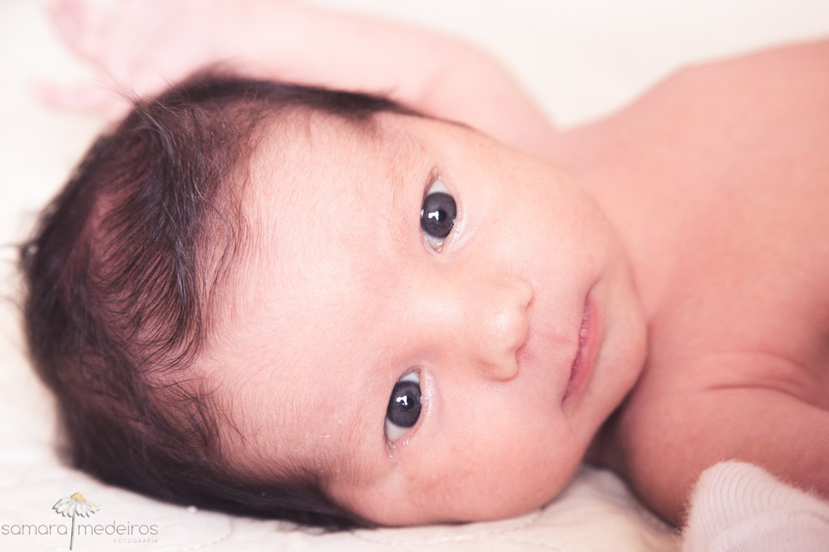 Close no rosto do bebê recém-nascido, com os olhinhos bem abertos, observando ao redor.