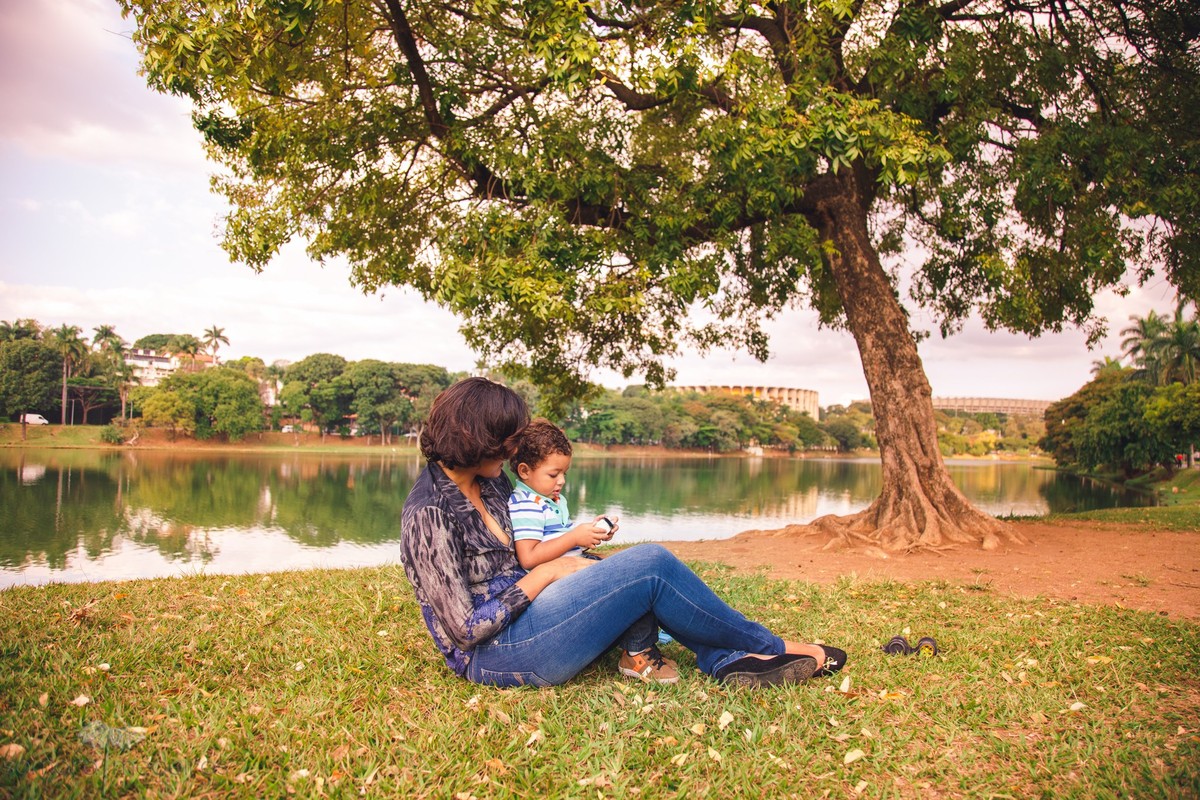 Mãe e filho sentados na grama brincando e se divertindo durante sessão de foto de família.