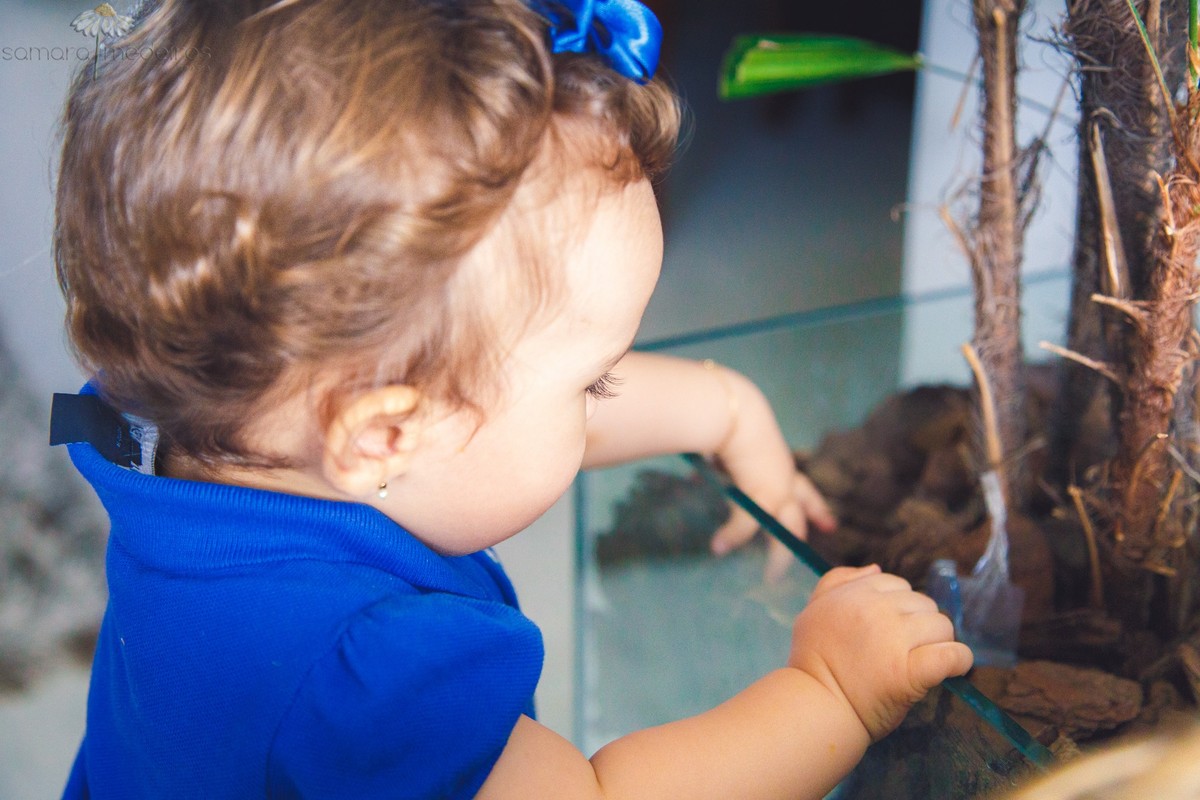 Criança de pé brincando com a planta em sua casa, em Belo Horizonte, durante uma sessão de fotos.