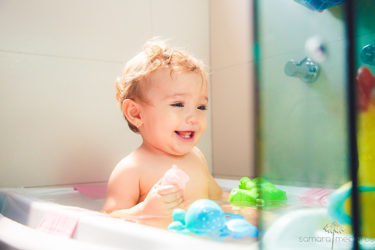 Criança em sua banheirinha tomando banho, para registro na sessão fotográfica lifestyle, em sua casa.
