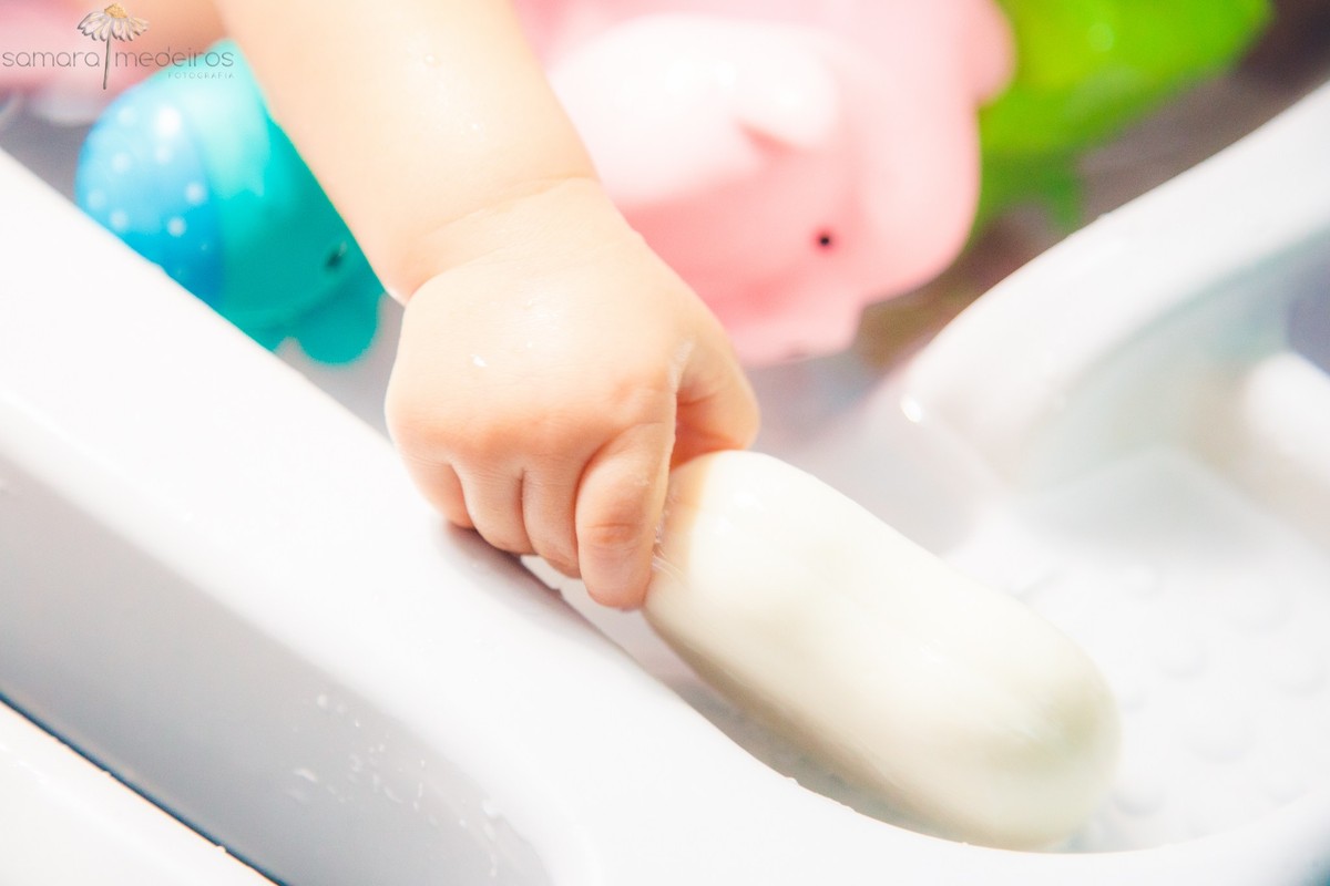 Detalhe da mão de uma criança pegando um sabonete, enquanto toma banho durante uma sessão de fotos infantil em sua casa, em Belo Horizonte.