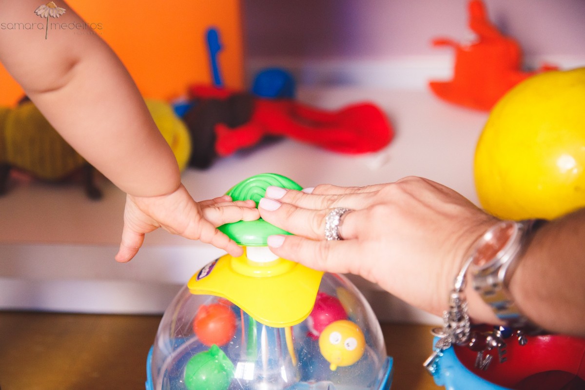 Detalhe da mão da mãe e filha brincando com um brinquedo no espaço kids do prédio, em Belo Horizonte.