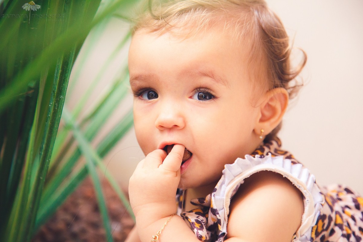 Close no rosto de uma criança colocando algo na boca, no play do prédio, onde ela tem costume de brincar.
