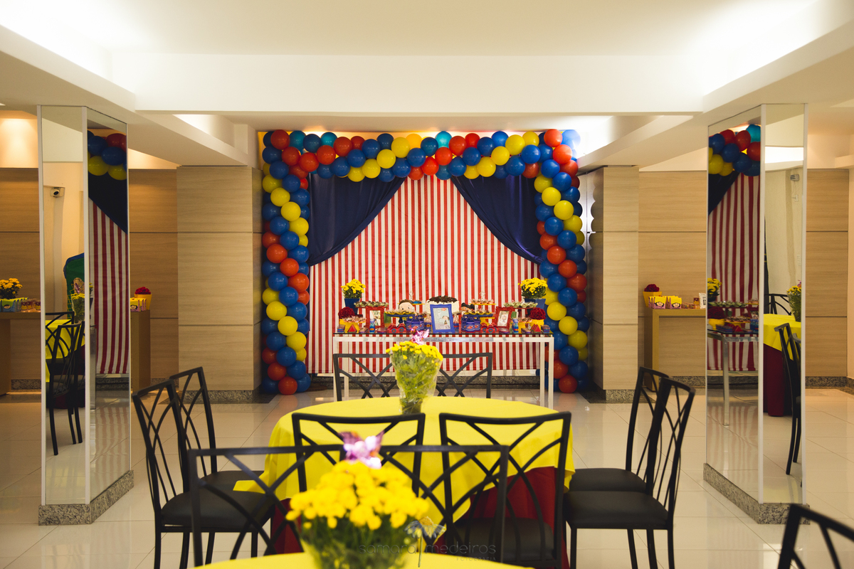 Visão ampla do salão de festas arrumado para um aniversário infantil, com tema O Show da Luna, com a mesa do bolo ao fundo.